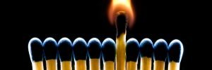 Many dark blue matches on a black background (one match burns).