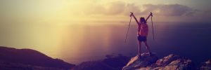 cheering young woman backpacker at sunrise seaside mountain peak