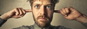 man with fingers in his ears not listening